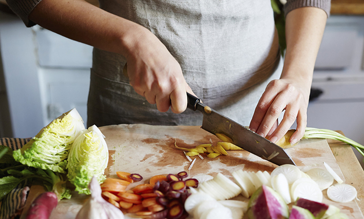 Woman cooking in kitchen with ingredients around her