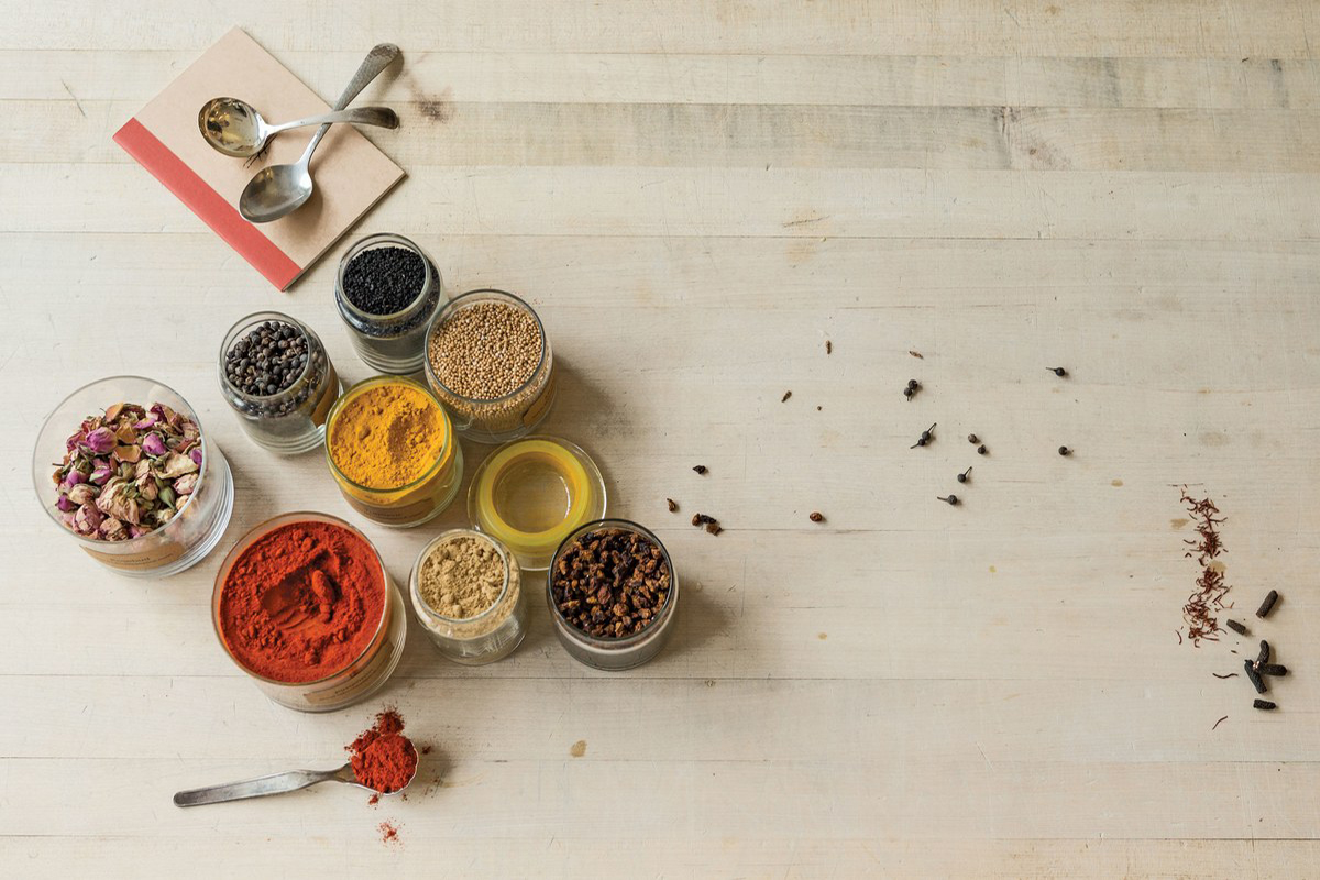 Assorted powder spices in wooden spoons on wood.